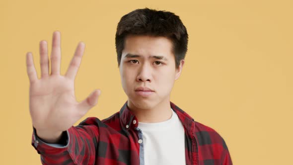 Asian Guy Gesturing Stop To Camera Shaking Head Orange Background