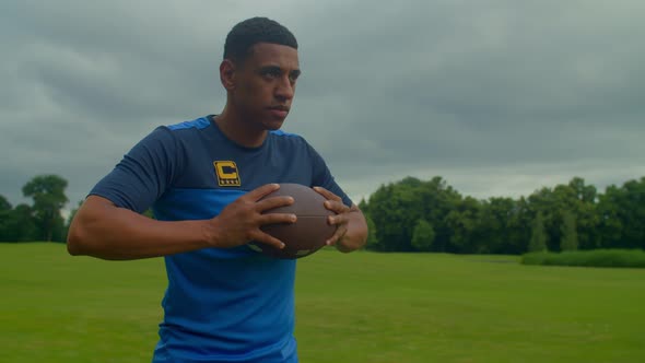 Portrait of Determined African American Football Player Holding Ball on Field