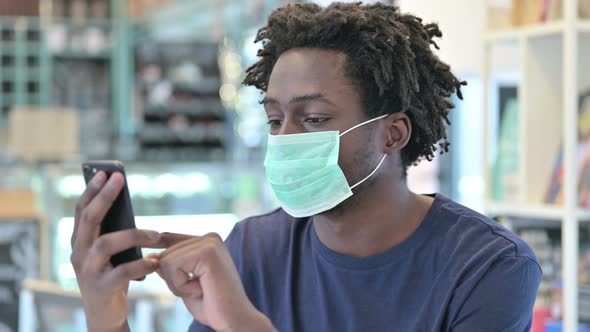 Portrait of African Man with Face Mask Using Smartphone