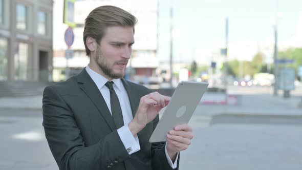 Upset Businessman Reacting to Loss on Tablet Outdoor