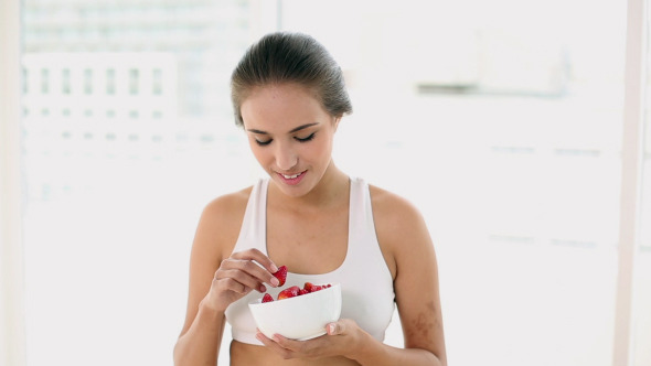 Fit Young Woman Eating A Bowl Of Strawberries