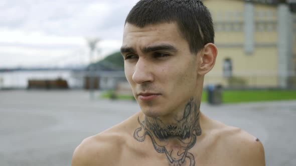 Portrait Young Man with a Tattoo on His Neck Standing Against the Sky with Clouds