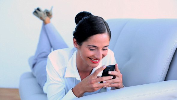 Attractive Businesswoman Lying On Couch Texting