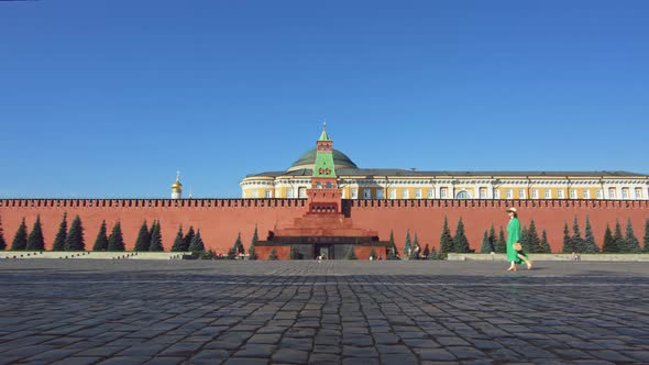 Beautiful girl in a green dress on an empty Red square in summer