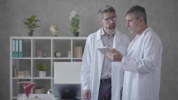Two Male Doctors Checking Information on the Tablet