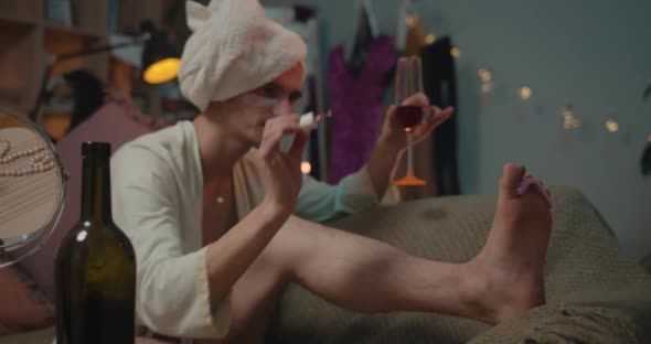 Relaxed Man Transgender Painting Toenails While Drinking Wine and Singing . Young Trans Man Doing