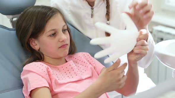 Close up of pretty girl and dentist playing with rubber glove