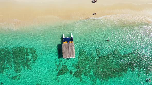 Touring boat with straw roof floating over calm clear water of turquoise sea over beautiful pattern