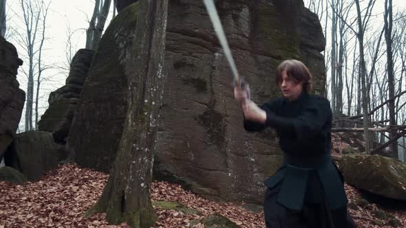 Man in Traditional Japanese Clothes, with a Sword, a Katana, Trains Martial Arts in the Forest