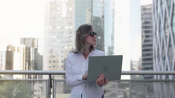 Focused businesswoman working on laptop computer in business district. 