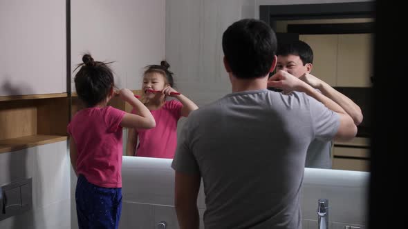 Asian Dad and Daughter Brushing Teeth in Bathroom