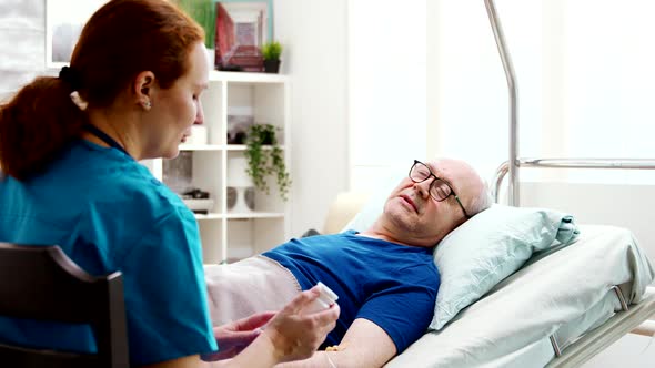 Nurse in Retirement Home Giving Prescription Pills To a Sick Lying in Hospital Bed Man