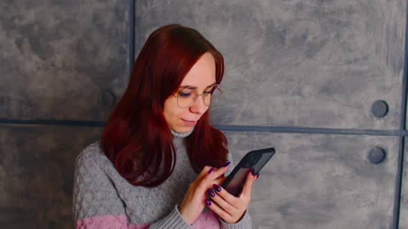 Serious Young Female with Dark Hair in Casual Clothes Using Smartphone