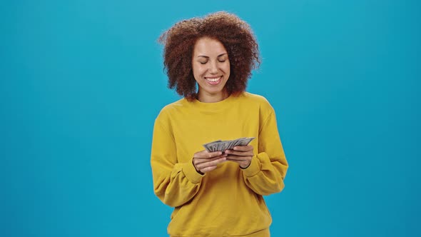 African American Woman in Yellow Sweater Counts Dollar Bills