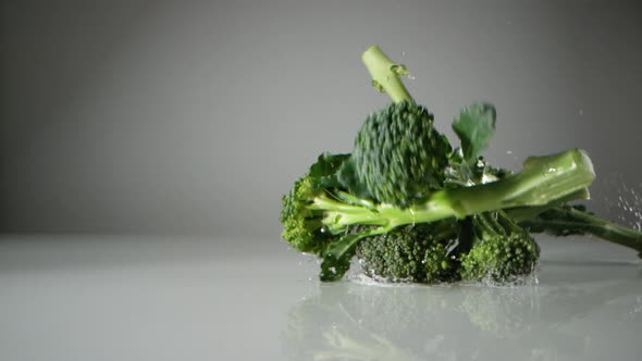 Broccoli falling on white surface. Slow Motion. alt