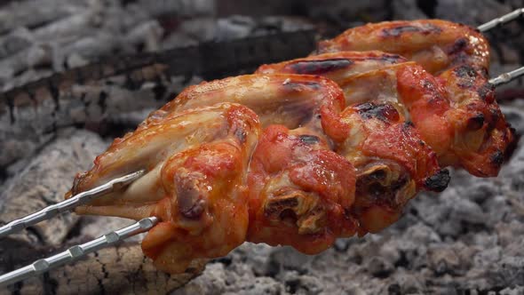 Mouthwatering Chicken Wings on the Skewers Are Flipped Above the Coals