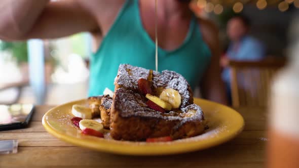 Slowmotion shot of a guy dripping honey over frenchtoast in a restaurant.