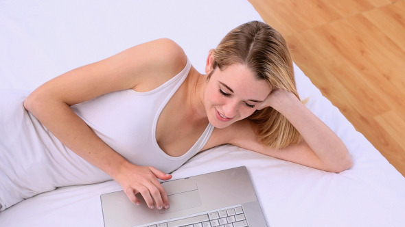 Happy Gorgeous Blonde Lying On Bed Using Laptop