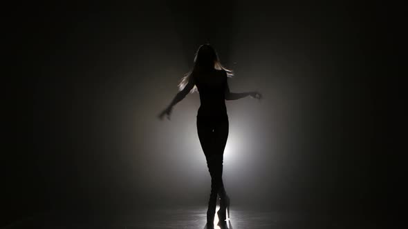 Silhouette of Woman Posing in Studio on Dark Background