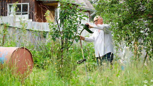 Old Man Cutting The Grass With Electric Mower