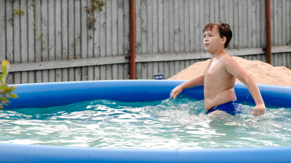 Boy Swimming In Inflatable Pool In The Yard