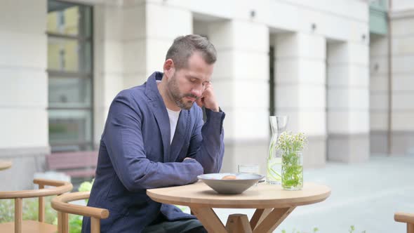 Tired Man Taking Nap While Sitting in Outdoor Cafe