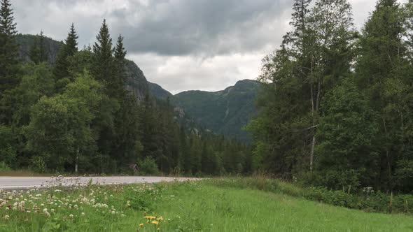 Mountain forest road, time lapse of cars driving on overcast day, zoom out