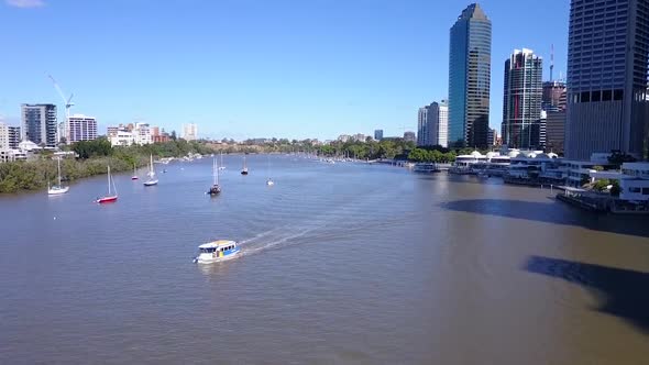 Aerial shot of City Ferry with tall city buildings along river Brisbane, Queensland