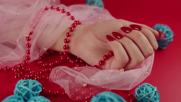 From Above of Crop Anonymous Woman with Red Beads and with Red Manicure on Red Background in Studio