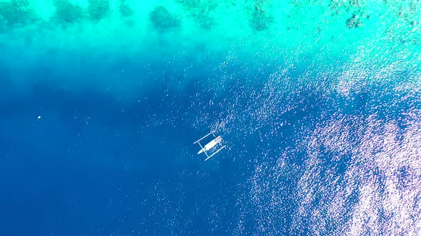 Indonesian boat Jukung floating on calm clear water of blue turquoise lagoon over coral reefs and ro