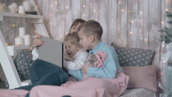 Young Lady Watches Movie on Tablet with Little Children