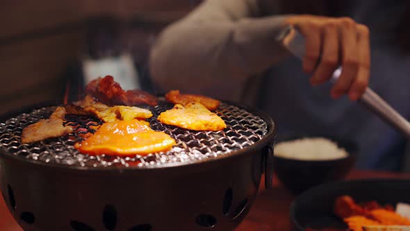 Young asian eating korean barbecue yakiniku in restaurant