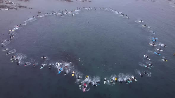 Paddle-out memorial in ocean for deceased surfer; human circle splashing water