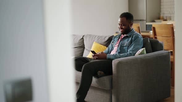 African laughing man texting by phone