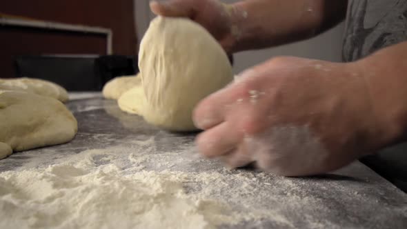 Men's hands hold dough. making raw dough for pizza, rolls or bread.