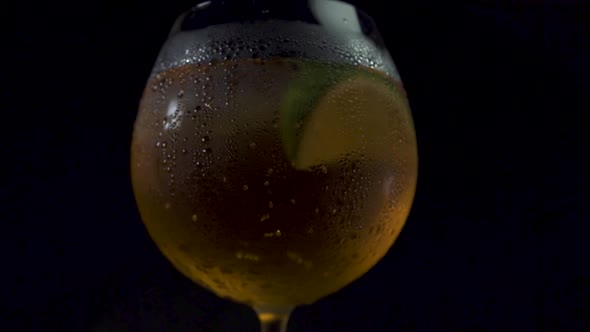 Cinematic Tilt Up Shot of a Glass of Alcoholic Drink in a Dark Background.