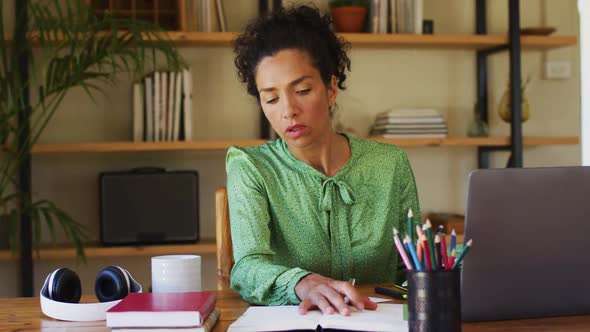 Mixed race woman taking notes while working from home