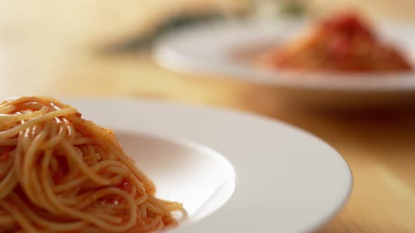 Camera follows putting fresh tomato sauce over pasta in plate. Slow Motion.