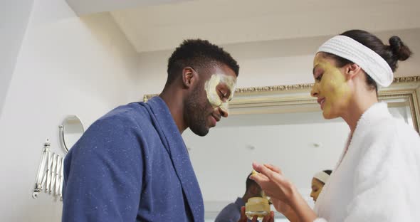 Happy diverse couple with doing make ups and looking at each other in bathroom