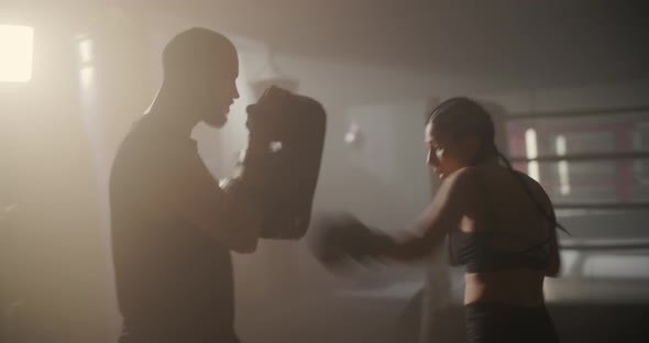 Young Woman Athlete in Boxing Gloves and Sport Clothes is Boxing With Her Skillful Trainer