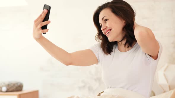 Young Attractive Woman Takes a Selfie Just After Waking Up