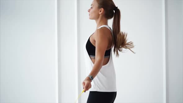 Young Woman with Fitness Tracker on Hand is Jumping Rope in Sports Club