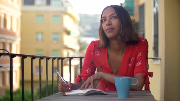 A woman writing in a journal diary traveling in a luxury resort town in Italy, Europe