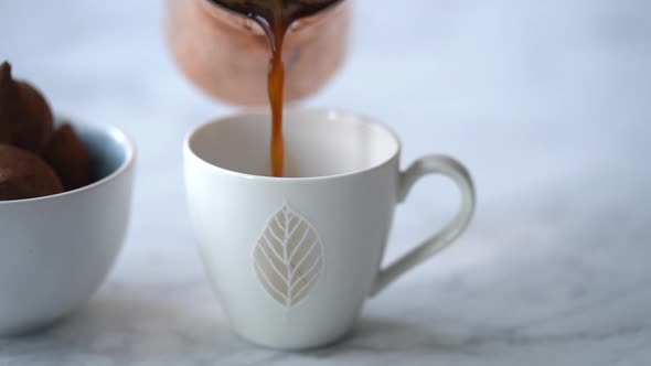 Woman pouring coffee from turk into cup