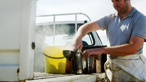 Beekeeper preparing bee smoker on truck