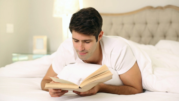 Smiling Handsome Man Reading In Bed