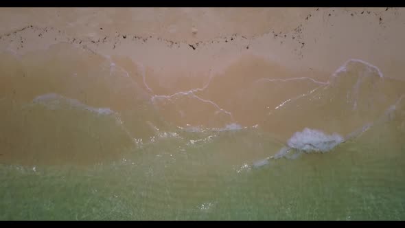 Aerial drone landscape of idyllic seashore beach trip by blue green ocean with white sandy backgroun