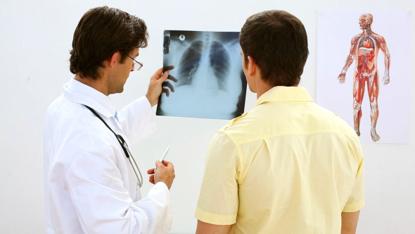 Smiling Doctor Looking At Xray With Patient