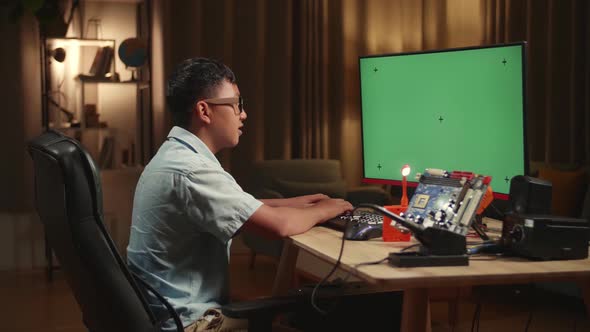 Engineer Asian Boy Is Working With Desktop Computer In Home, Mock Up Green Screen Display