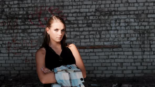 Beautiful Young Woman Standing Near the Brick Wall and Looking at the Camera